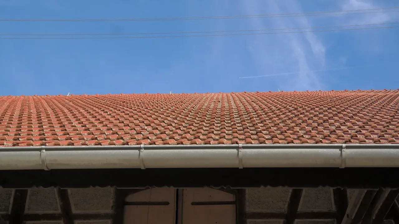 Red tiled roof with a long metal gutter along the edge